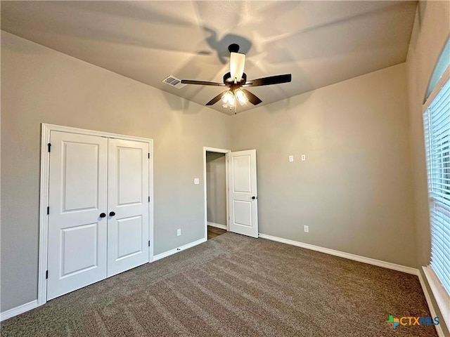 unfurnished bedroom with a closet, dark colored carpet, and ceiling fan