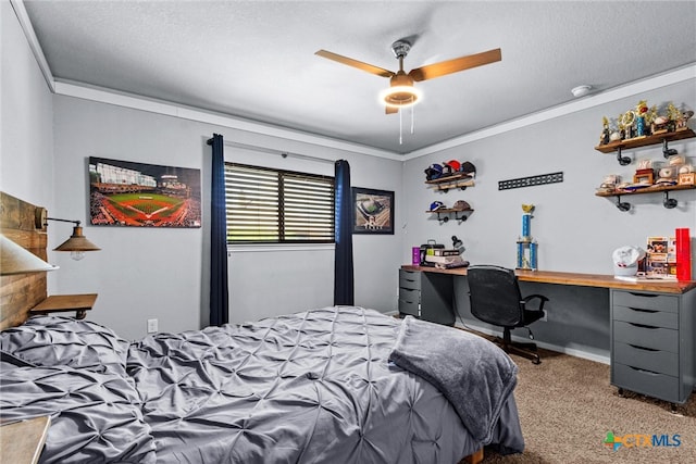 carpeted bedroom with a textured ceiling, ceiling fan, built in desk, and crown molding