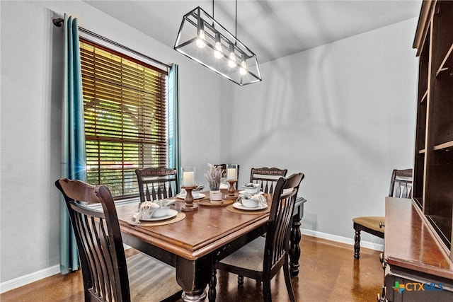 dining space with finished concrete floors, baseboards, and a chandelier