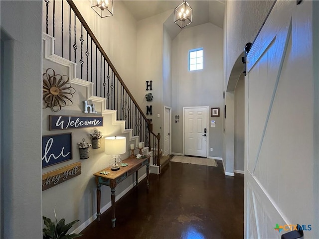 foyer entrance with a notable chandelier, stairway, a high ceiling, concrete flooring, and baseboards