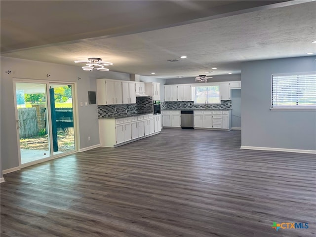 kitchen featuring dark wood-type flooring, a wealth of natural light, stainless steel dishwasher, and white cabinetry