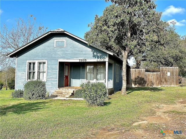 bungalow-style home with a front lawn and fence