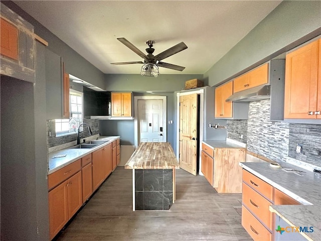 kitchen featuring backsplash, ceiling fan, sink, a center island, and dark hardwood / wood-style floors