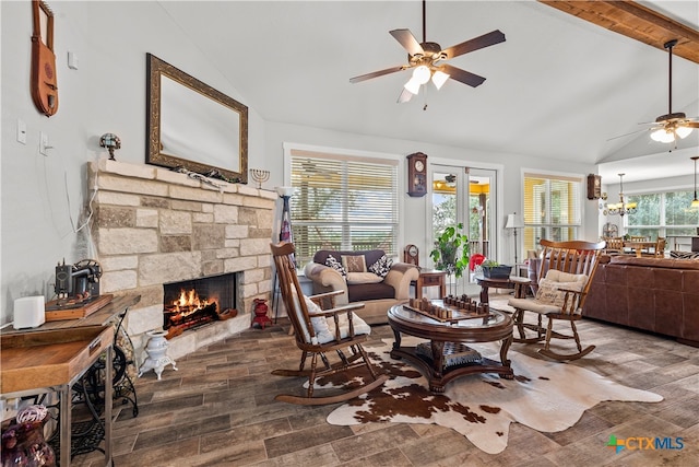 sitting room featuring lofted ceiling with beams, a stone fireplace, dark hardwood / wood-style floors, and ceiling fan with notable chandelier