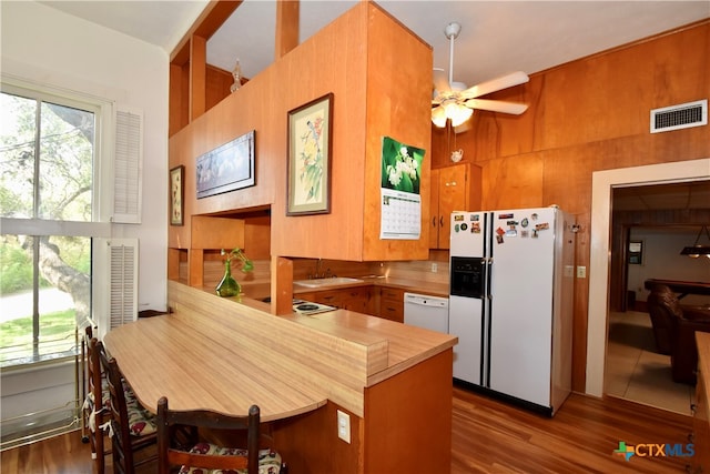 kitchen with kitchen peninsula, white appliances, ceiling fan, and dark hardwood / wood-style floors