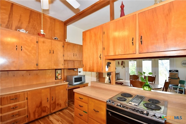 kitchen with light wood-type flooring, stainless steel appliances, beamed ceiling, and ceiling fan