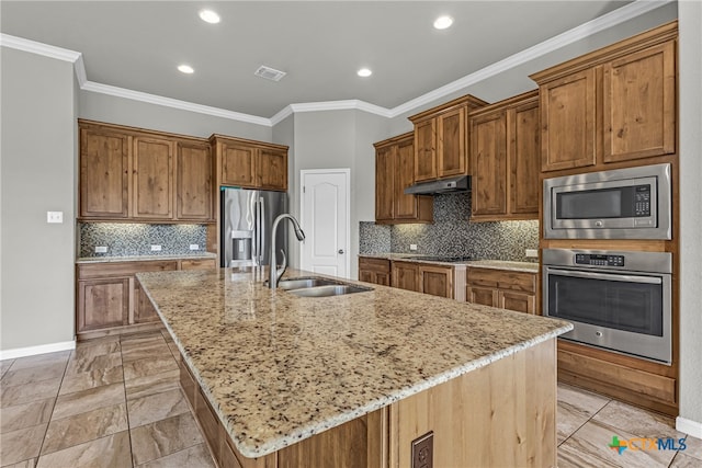 kitchen featuring light stone counters, sink, an island with sink, ornamental molding, and appliances with stainless steel finishes