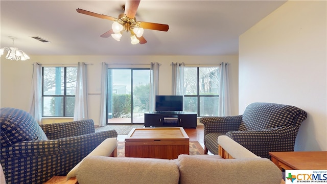 living room with ceiling fan with notable chandelier and hardwood / wood-style flooring