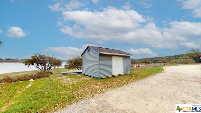 view of outbuilding featuring a water view and a yard