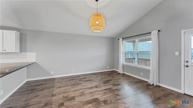 unfurnished dining area featuring lofted ceiling and dark hardwood / wood-style floors