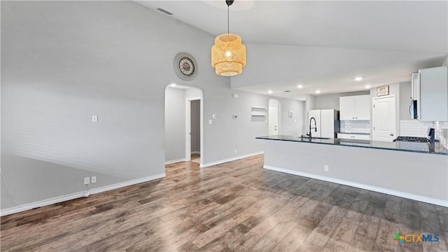 kitchen with white fridge, pendant lighting, dark hardwood / wood-style floors, white cabinets, and backsplash