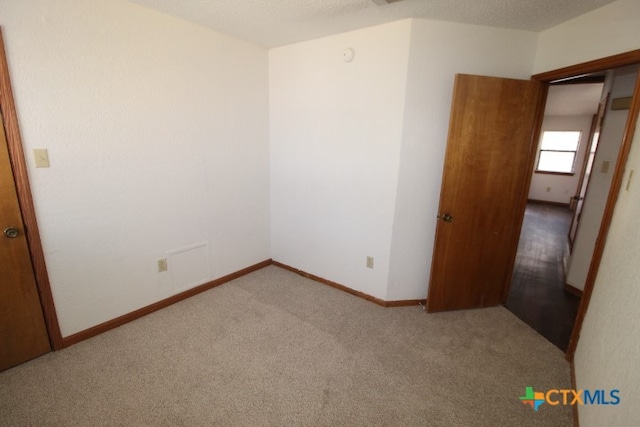 carpeted empty room featuring a textured ceiling