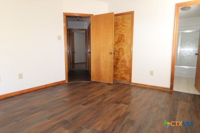 unfurnished bedroom featuring connected bathroom and dark hardwood / wood-style flooring