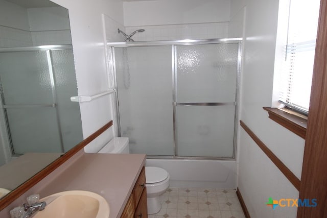 full bathroom with bath / shower combo with glass door, vanity, and toilet