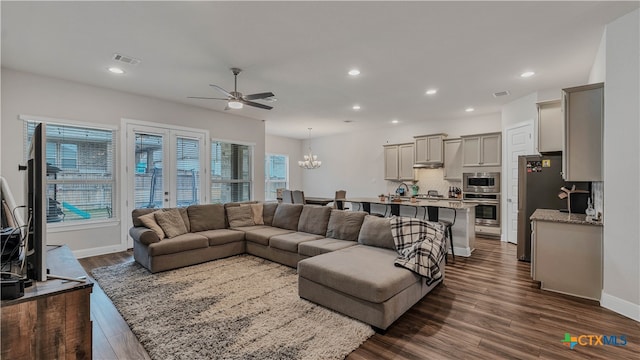 living room with ceiling fan with notable chandelier, dark hardwood / wood-style floors, and a healthy amount of sunlight