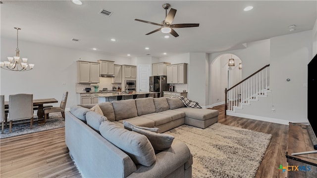 living room with light hardwood / wood-style flooring and ceiling fan with notable chandelier