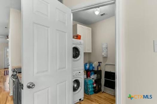 2303 Schwald Rd, Killeen, TX 76543 - laundry area with estacked washer and dryer, light wood-style flooring, and cabinet space