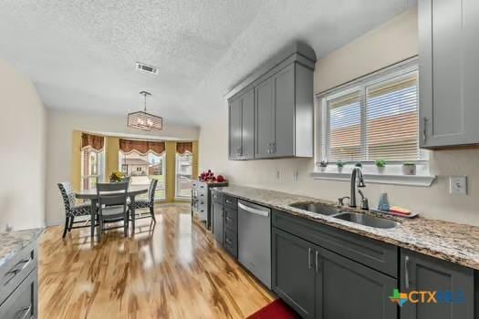 2303 Schwald Rd, Killeen, TX 76543 - kitchen with dishwasher, a sink, light wood-style floors, gray cabinets, and light stone counters