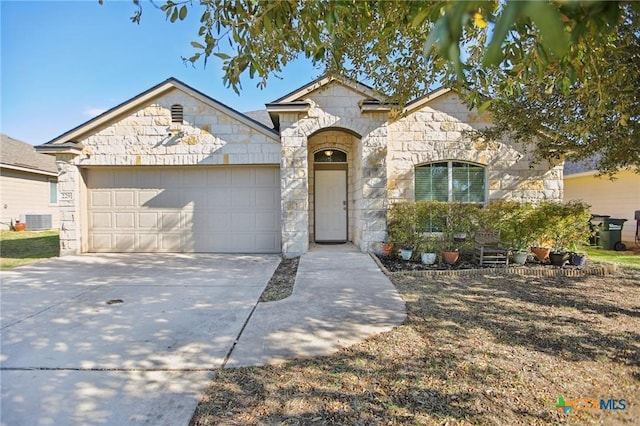 view of front of house with an attached garage, cooling unit, stone siding, and driveway