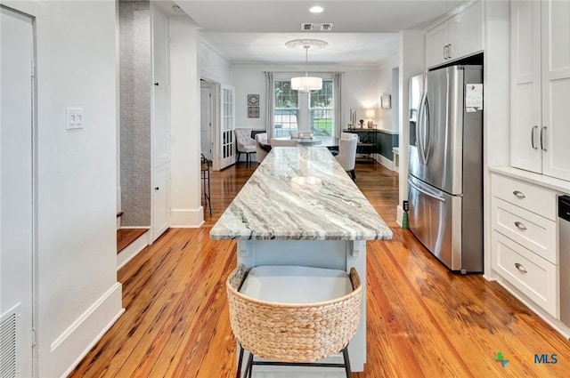 406 S Liberty St, Victoria, TX 77901 - kitchen featuring stainless steel fridge, a center island, white cabinetry, visible vents, and light wood finished floors