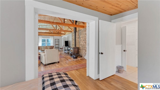 corridor featuring hardwood / wood-style floors, wooden ceiling, beam ceiling, and brick wall