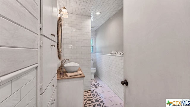 bathroom with tile walls, vanity, and toilet