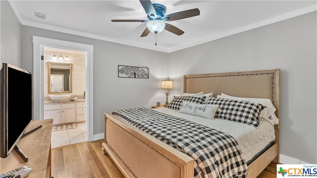 bedroom with ensuite bathroom, light hardwood / wood-style floors, and ceiling fan