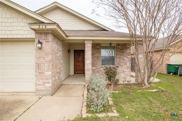 entrance to property featuring a garage, brick siding, a lawn, and a shingled roof