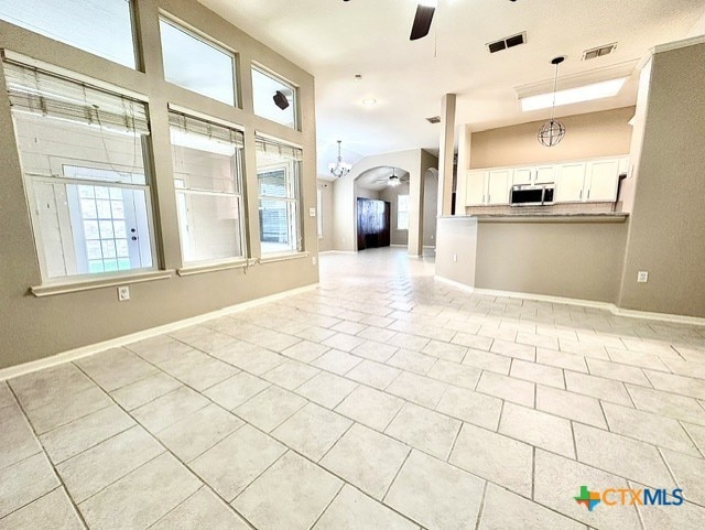 214 Yellowstone Dr, Victoria, TX 77904 - unfurnished living room featuring a ceiling fan, light tile patterned flooring, arched walkways, and plenty of natural light