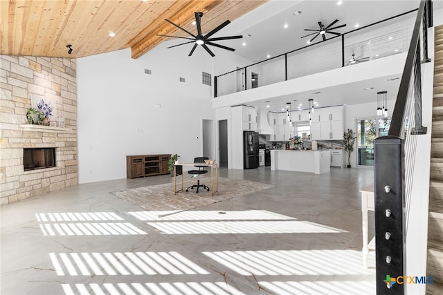 unfurnished living room featuring high vaulted ceiling, beam ceiling, ceiling fan, and a fireplace