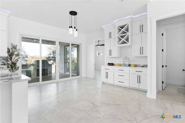 bar featuring pendant lighting, light stone counters, and white cabinetry