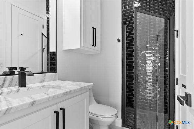 bathroom featuring an enclosed shower, vanity, and toilet