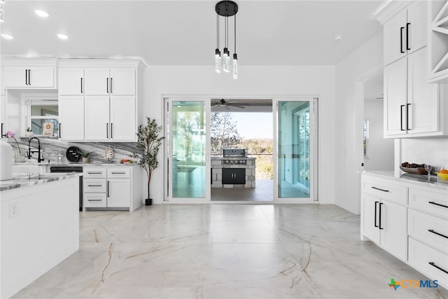 kitchen with white cabinets, decorative light fixtures, sink, backsplash, and ceiling fan