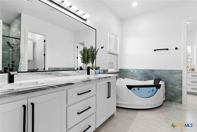 bathroom with tile walls, a bathtub, and vanity