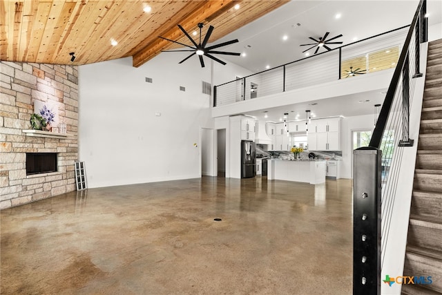 unfurnished living room with wood ceiling, high vaulted ceiling, beamed ceiling, and a fireplace