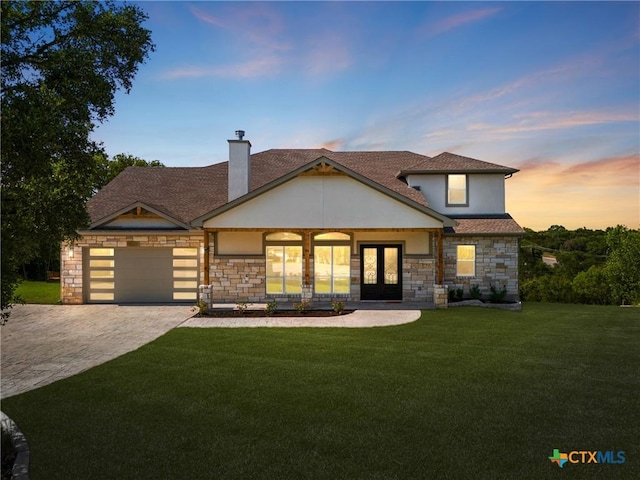 view of front of property with french doors, a lawn, and a garage