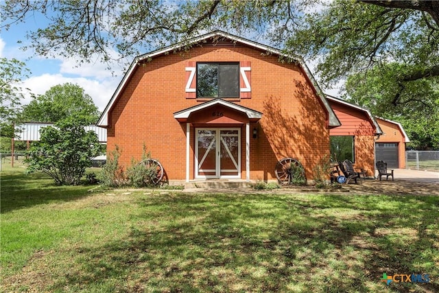 view of front of property with fence, brick siding, an attached garage, a gambrel roof, and a front yard