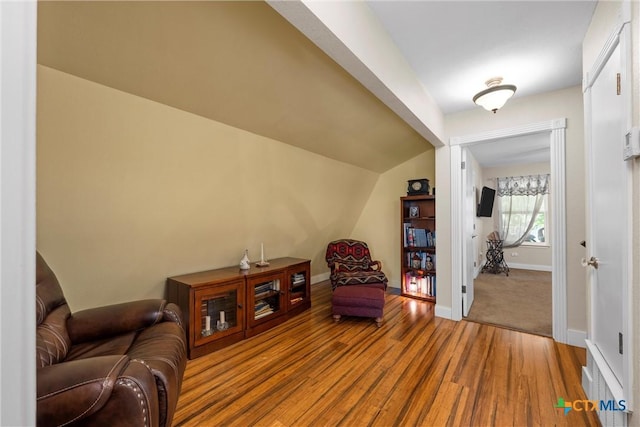sitting room featuring vaulted ceiling, baseboards, and wood finished floors