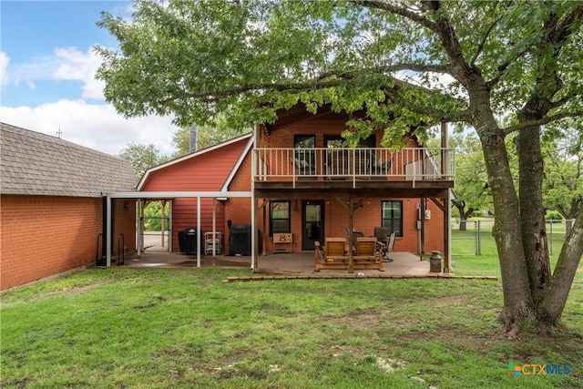 back of property with fence, brick siding, a patio area, a lawn, and a balcony