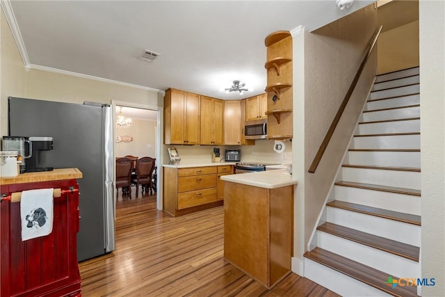 kitchen featuring stainless steel appliances, visible vents, light wood-style floors, crown molding, and light countertops
