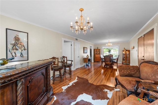 living area featuring light wood-style flooring, visible vents, a chandelier, and ornamental molding