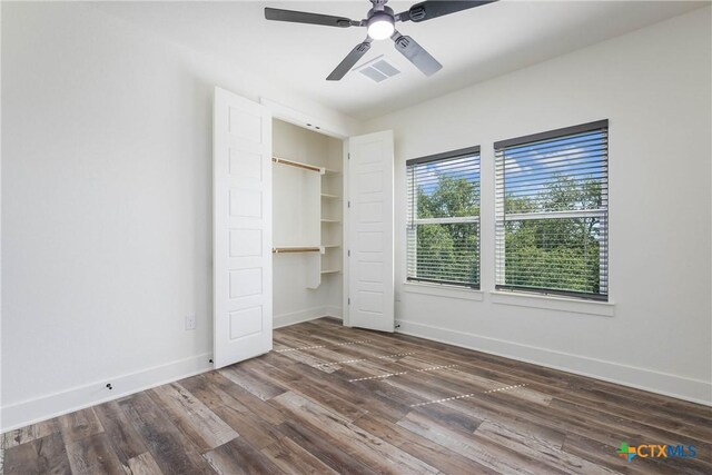 unfurnished bedroom featuring baseboards, visible vents, ceiling fan, dark wood-style flooring, and a closet