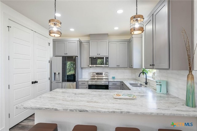 kitchen featuring hanging light fixtures, a breakfast bar area, appliances with stainless steel finishes, and a sink