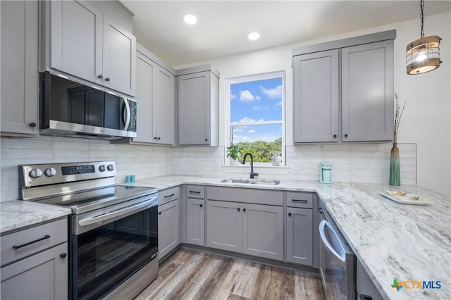 kitchen featuring appliances with stainless steel finishes, gray cabinets, a sink, and decorative light fixtures