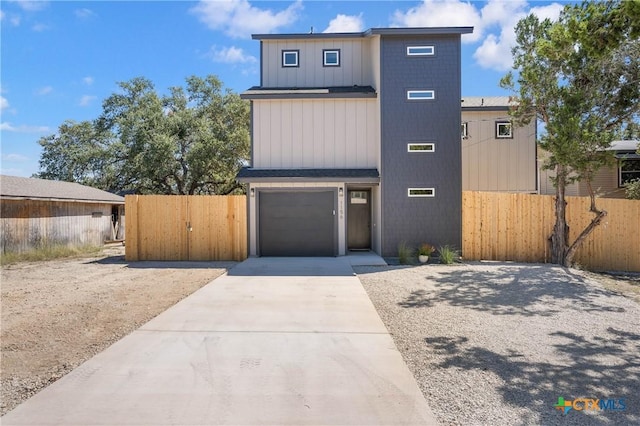 view of front of home with a garage, concrete driveway, fence, and a gate