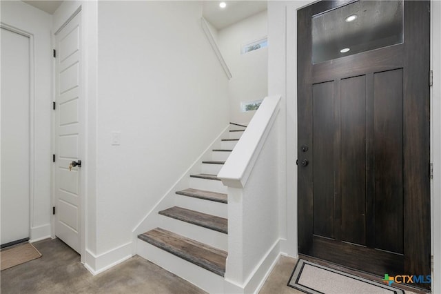 entrance foyer with recessed lighting, concrete floors, stairway, and baseboards