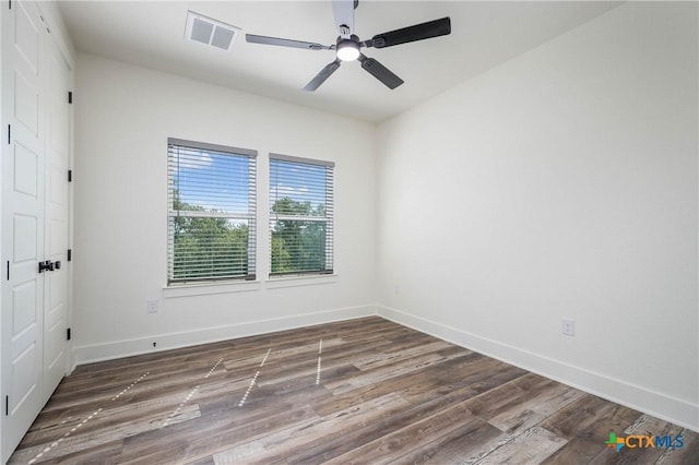 unfurnished room with dark wood-style floors, baseboards, visible vents, and ceiling fan