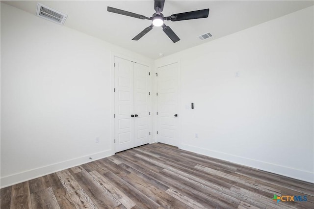 empty room with wood finished floors, visible vents, and baseboards