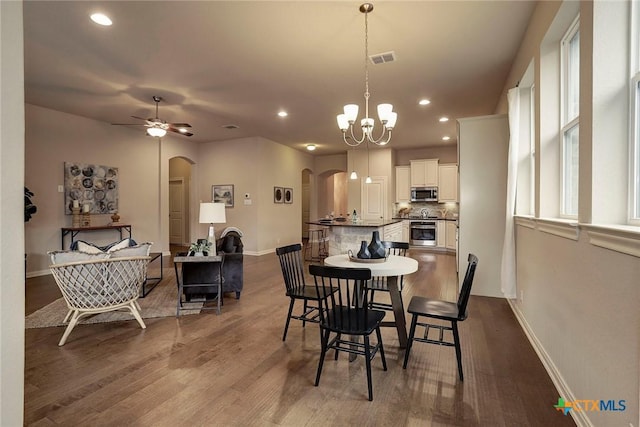 dining space featuring ceiling fan with notable chandelier and hardwood / wood-style floors