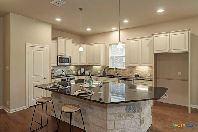 kitchen with sink, appliances with stainless steel finishes, white cabinetry, a kitchen breakfast bar, and a center island